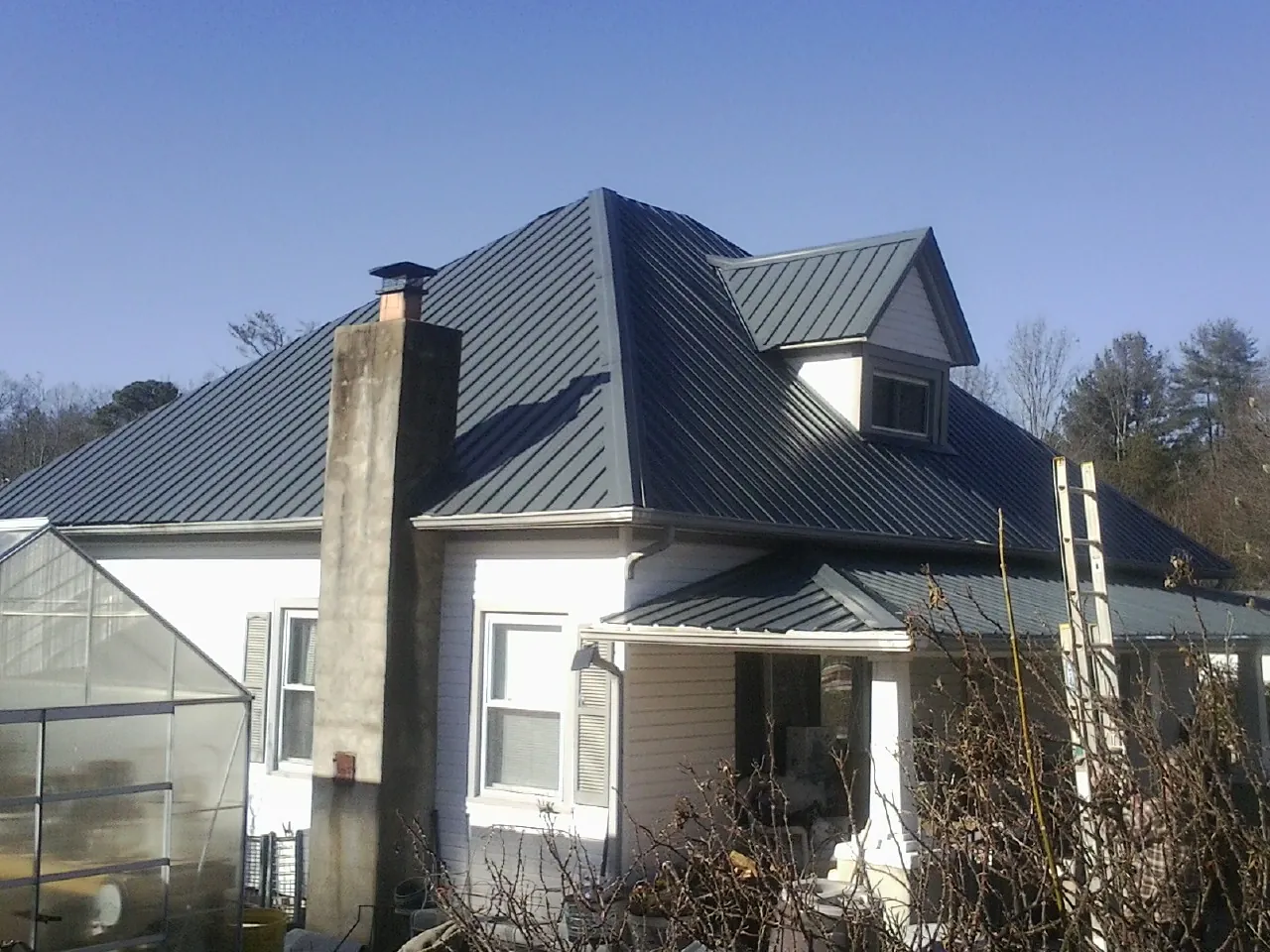 Dark blue standing seam metal roof on a white farmhouse with dormer — Slate & Tile Roof Repair by Roofing Brothers in Edna