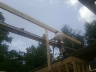 Carpenter setting a ridge beam over a new addition frame — Ice Dam Removal by Roofing Brothers in Edna