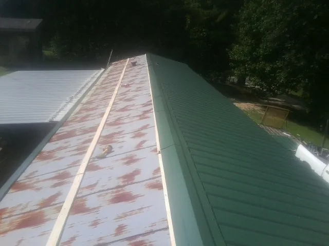 Old rusted panels beside newly installed green metal roofing — Wind Damage Roof Repair by Roofing Brothers in Edna