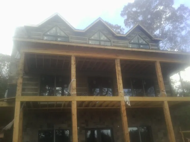 Dormers and porch framing on a large log home under construction — Roof Coating work by our crew in Edna