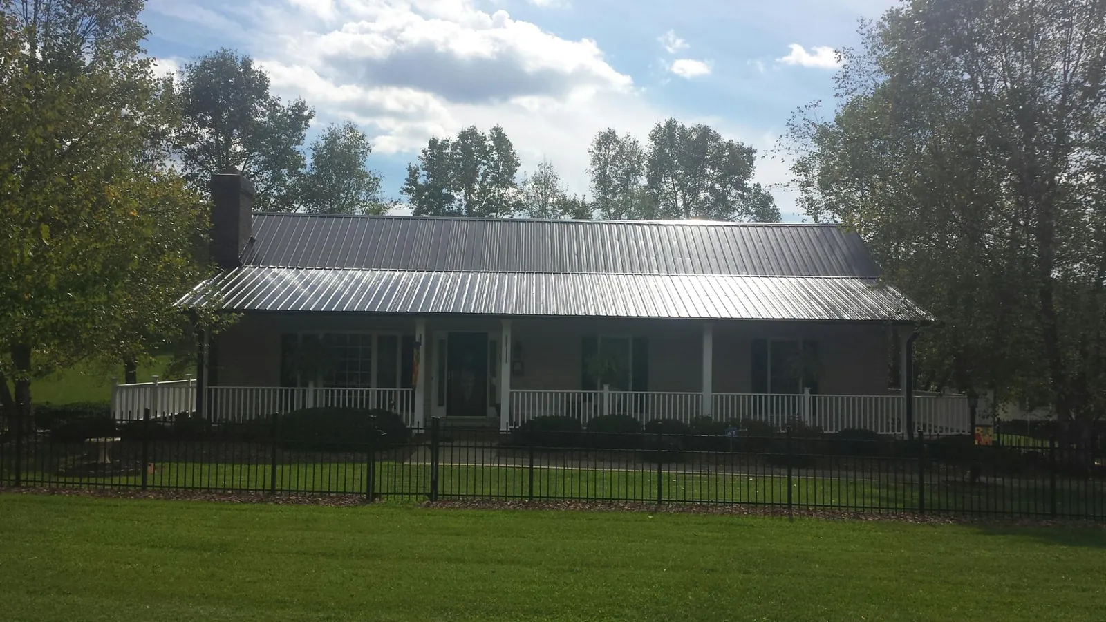 Gray metal roof on a brick ranch with a full width front porch — Gutter Guard Installation work by our crew in Edna
