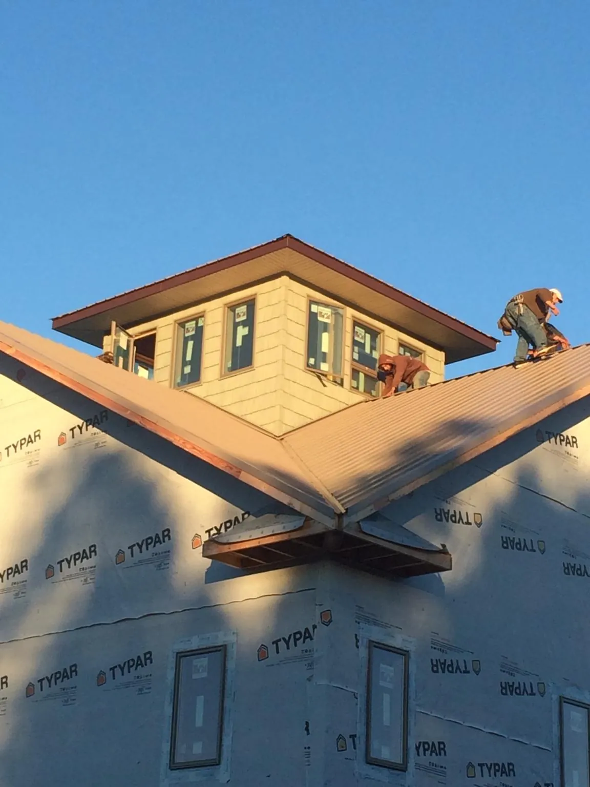 Roofers working around a rooftop cupola on a new metal roof at sunset — Roof Waterproofing in Edna by Roofing Brothers